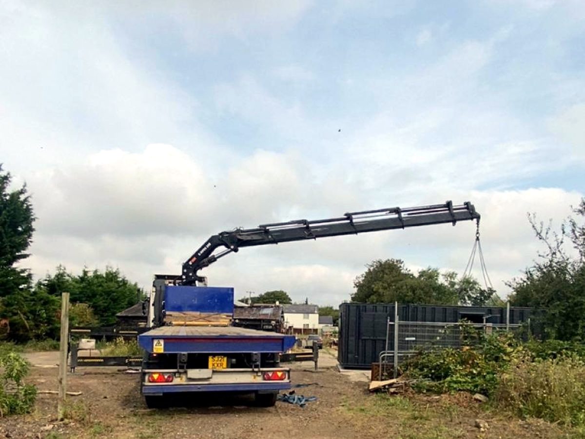 HIAB transporting a green GRP cabinet between sites.