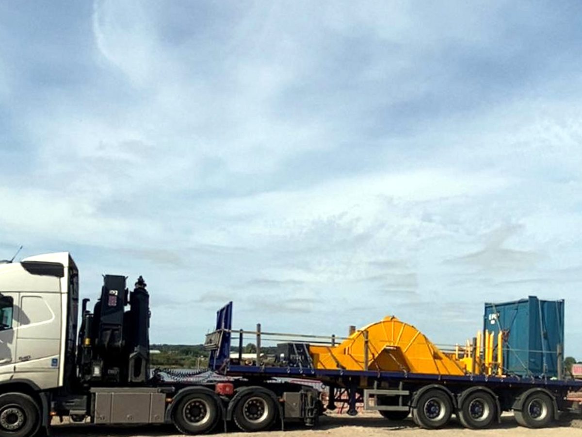 Yellow construction plant on an AC Lifting low-loader at the Preston yard.