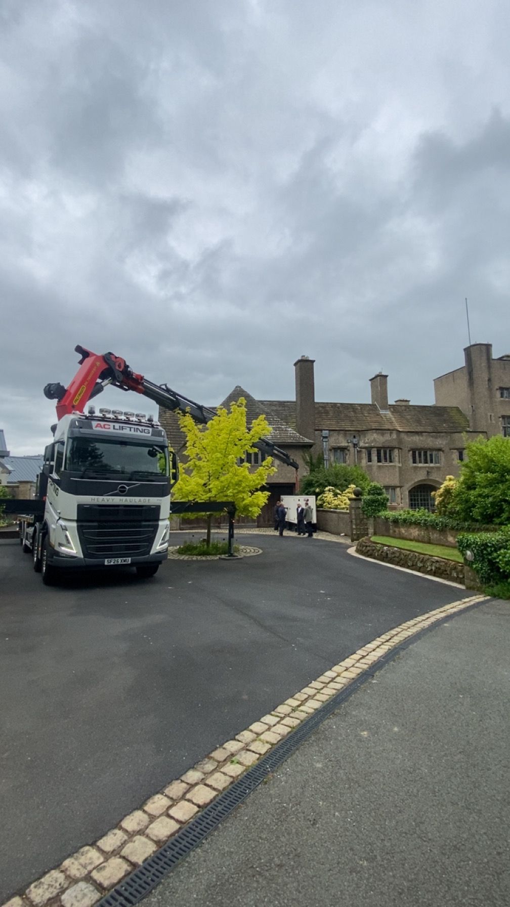 AC Lifting branded HIAB rig parked on a manor-house driveway, ready for a generator install.