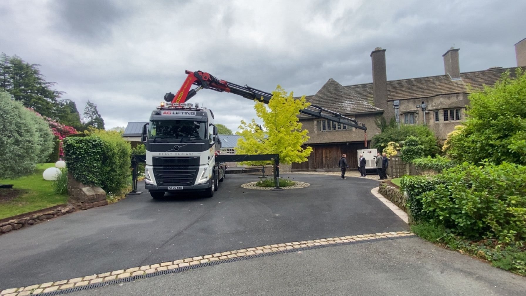 AC Lifting HIAB craning a generator into position on a residential driveway.