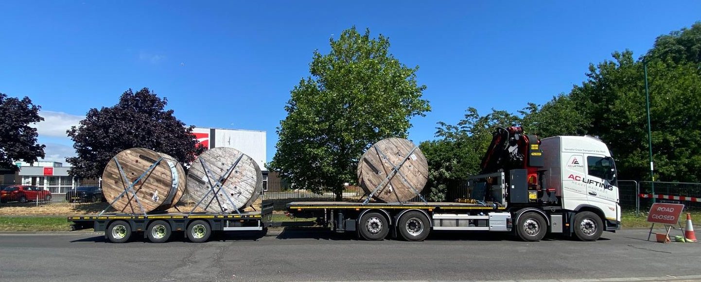 AC Lifting lorry and trailer delivering large cable drums under a road closure.