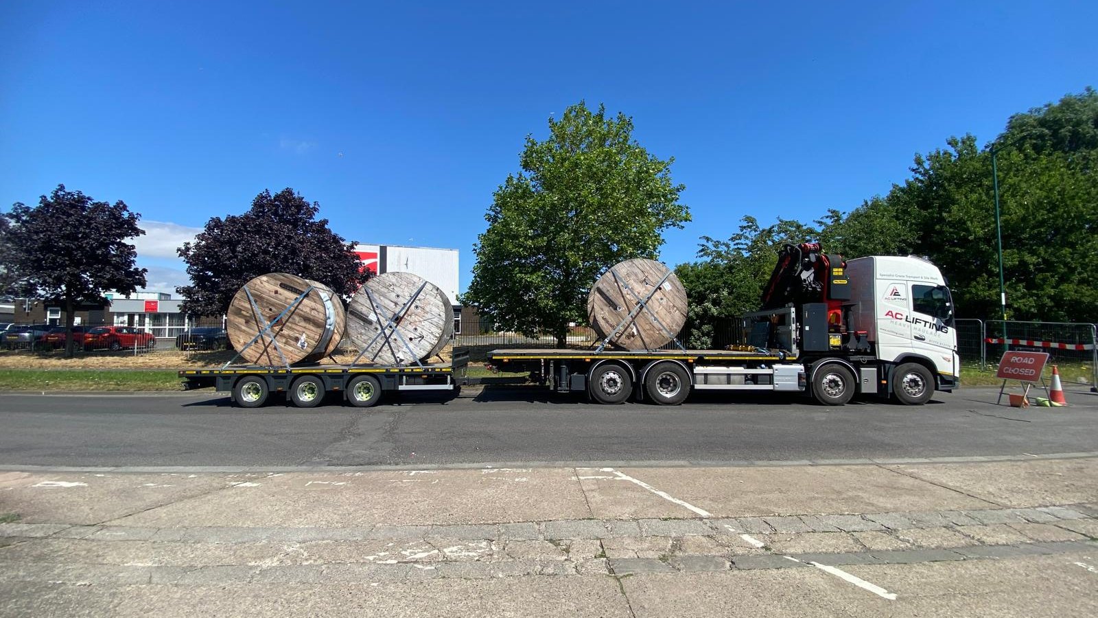 AC Lifting lorry and trailer delivering large cable drums under a road closure.