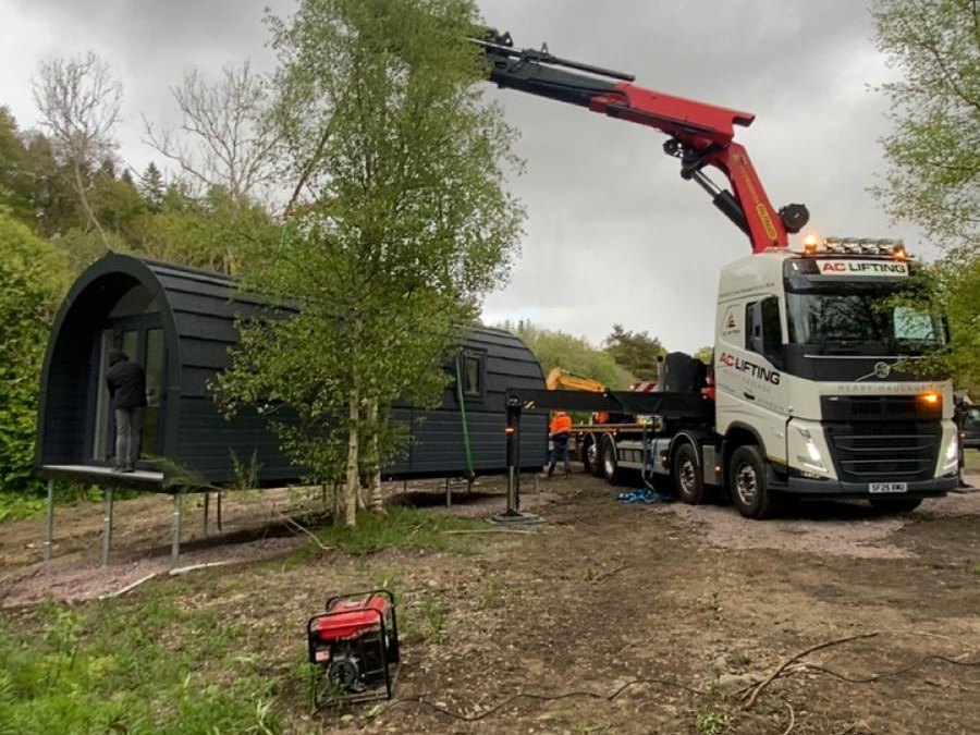 AC Lifting HIAB craning a modular garden pod into position on a rural plot.