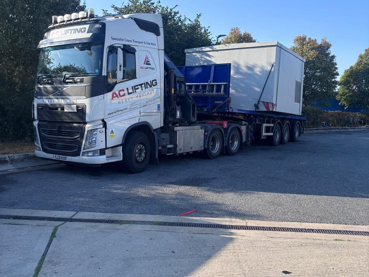 AC Lifting lorry and trailer delivering a modular cabin to site.